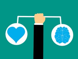 Brain and heart on opposite scales held up by an arm